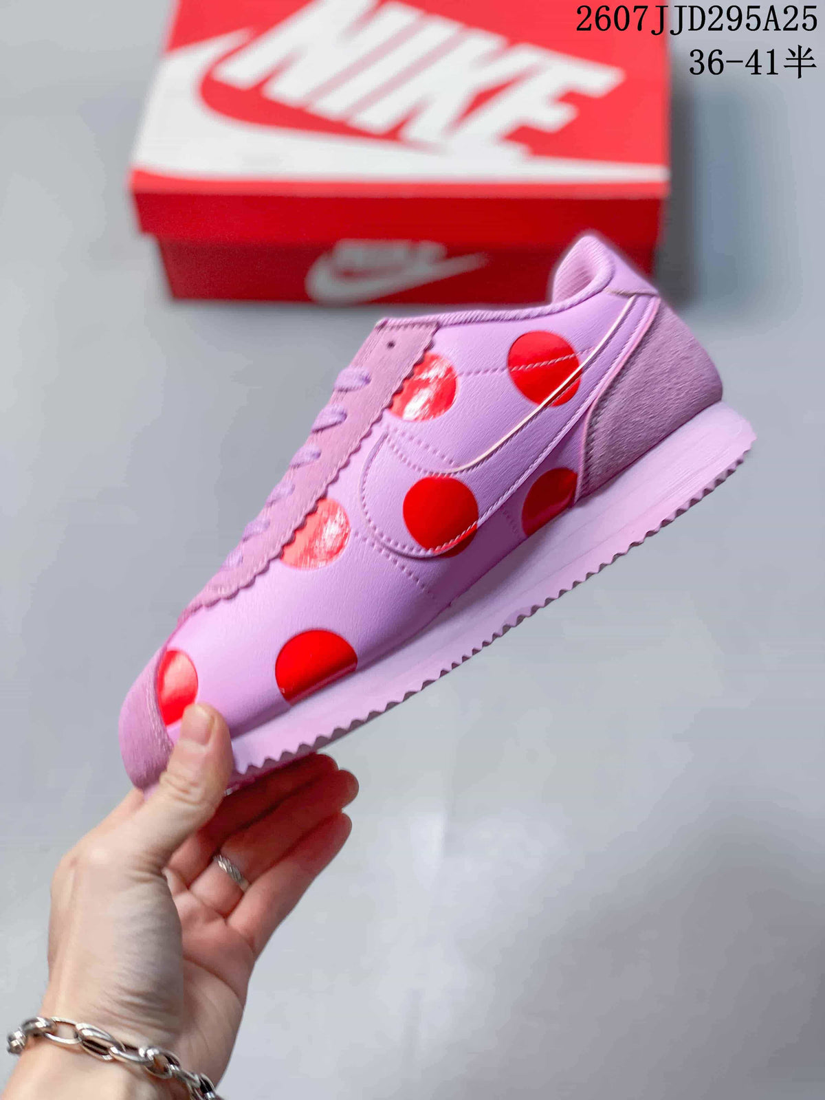 Side profile showing the pink upper, red circular accents, Swoosh branding, and textured outsole.
