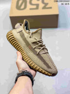 Angled side view of a beige Adidas Yeezy Boost 350 sneaker showing the side stripe, lace system, and tan ribbed outsole.