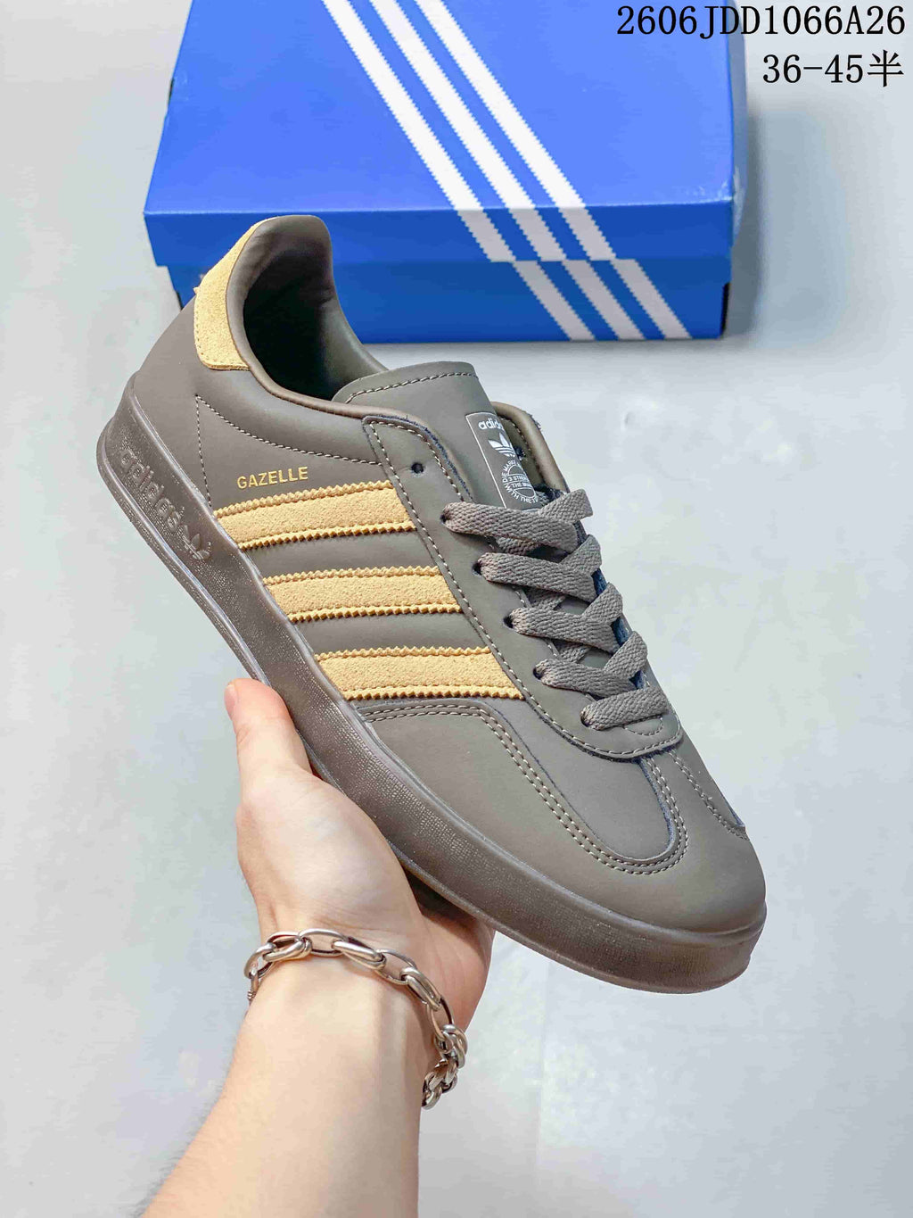 Angled side view showing Gazelle branding, gray upper panels, gold-toned stripes, and the textured outsole.