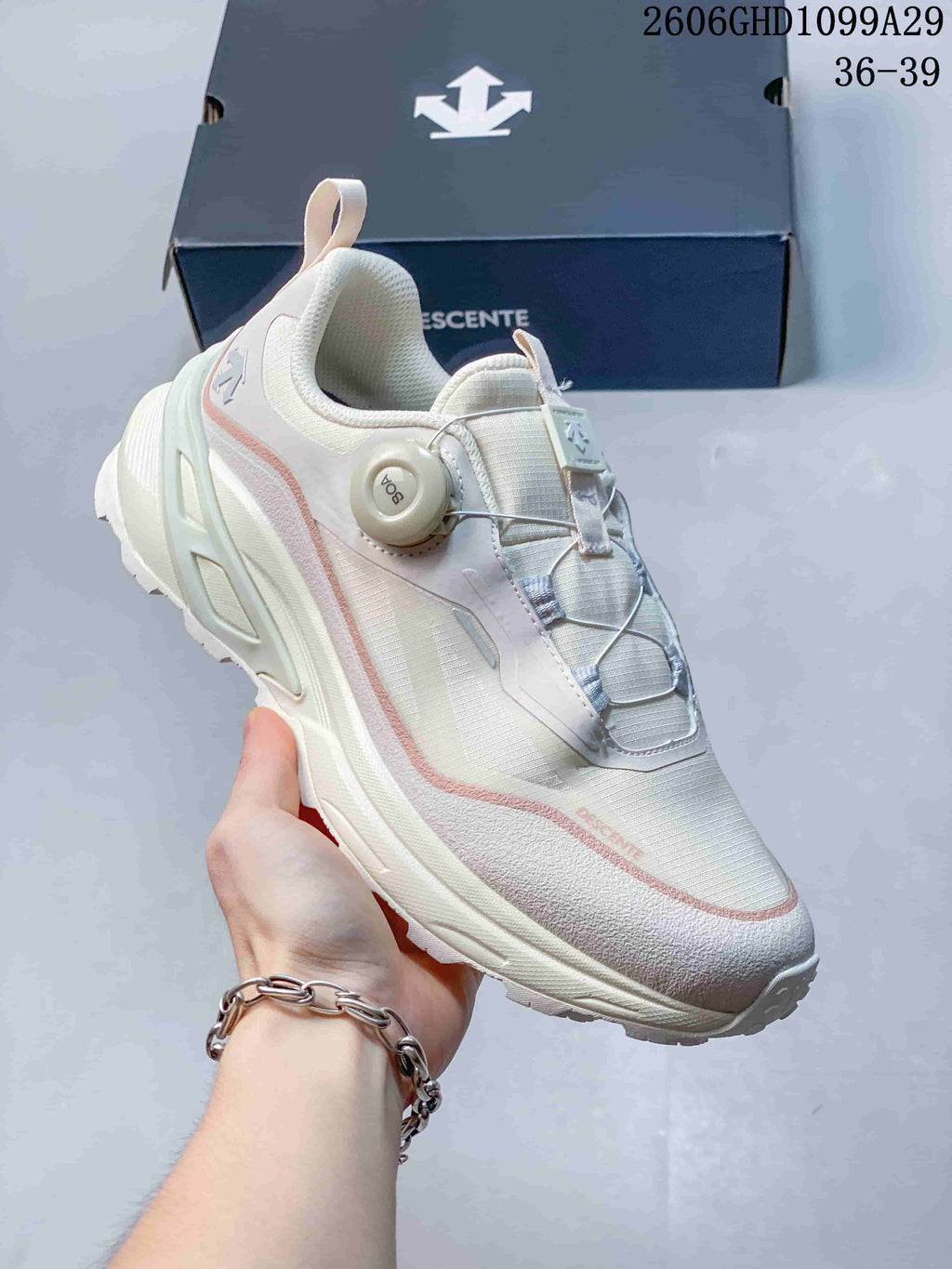 Angled close-up of the sneaker upper, wire lacing dial and pale pink details