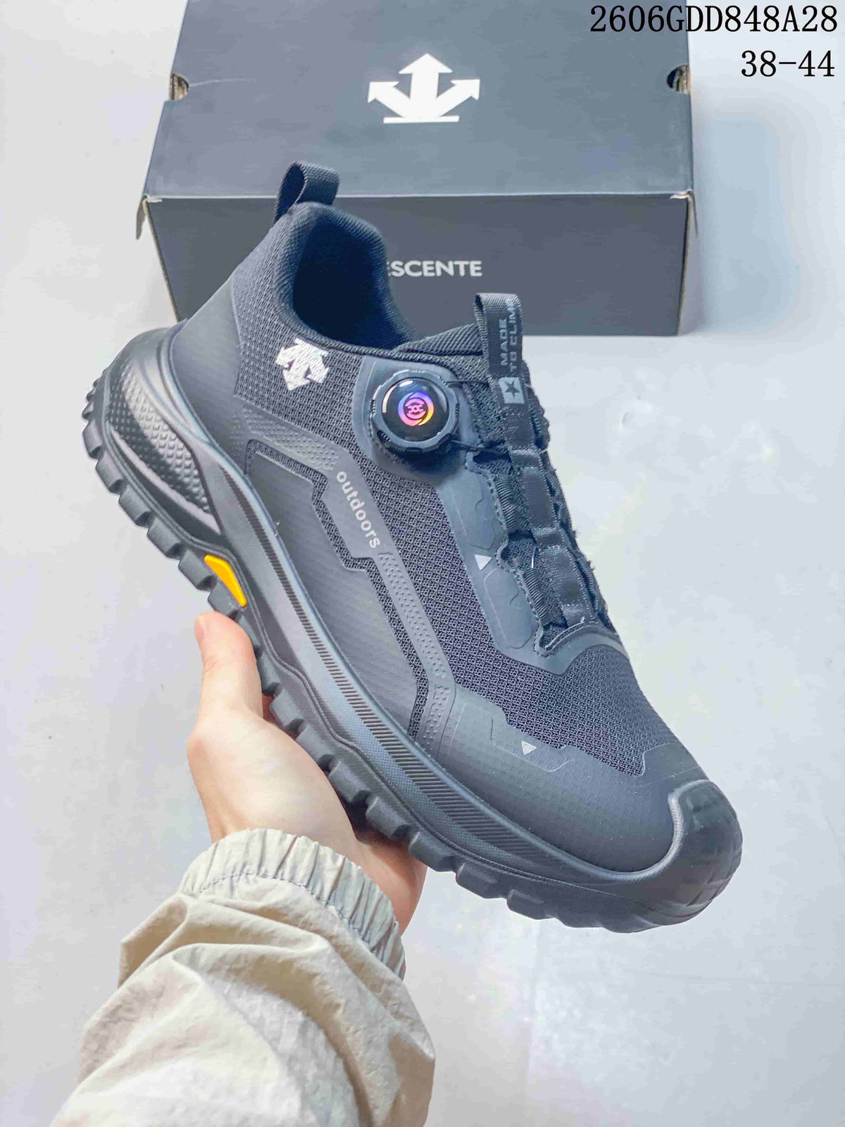 Angled side view of a charcoal DESCENTE shoe with dial closure and treaded outsole; image states sizes 38–44 and style code 2606GDD848A28.