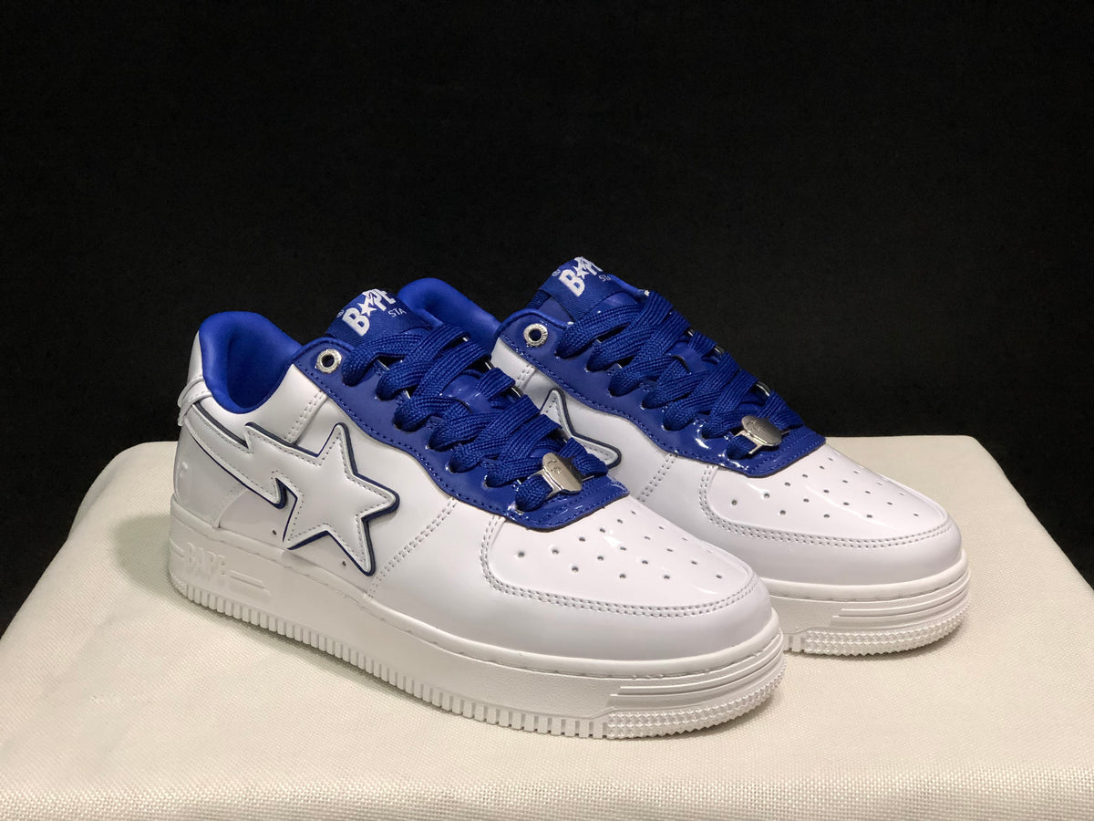 Three-quarter front view of the pair highlighting the white uppers, blue overlays, star-shaped side details, and perforated toe boxes.