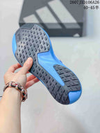 Bottom view of the blue and white sneaker showing the black rubber outsole with diamond-shaped traction details and blue midsole sections.