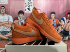 Pair of orange Nike low-top sneakers with tan Swooshes, shown from angled side views