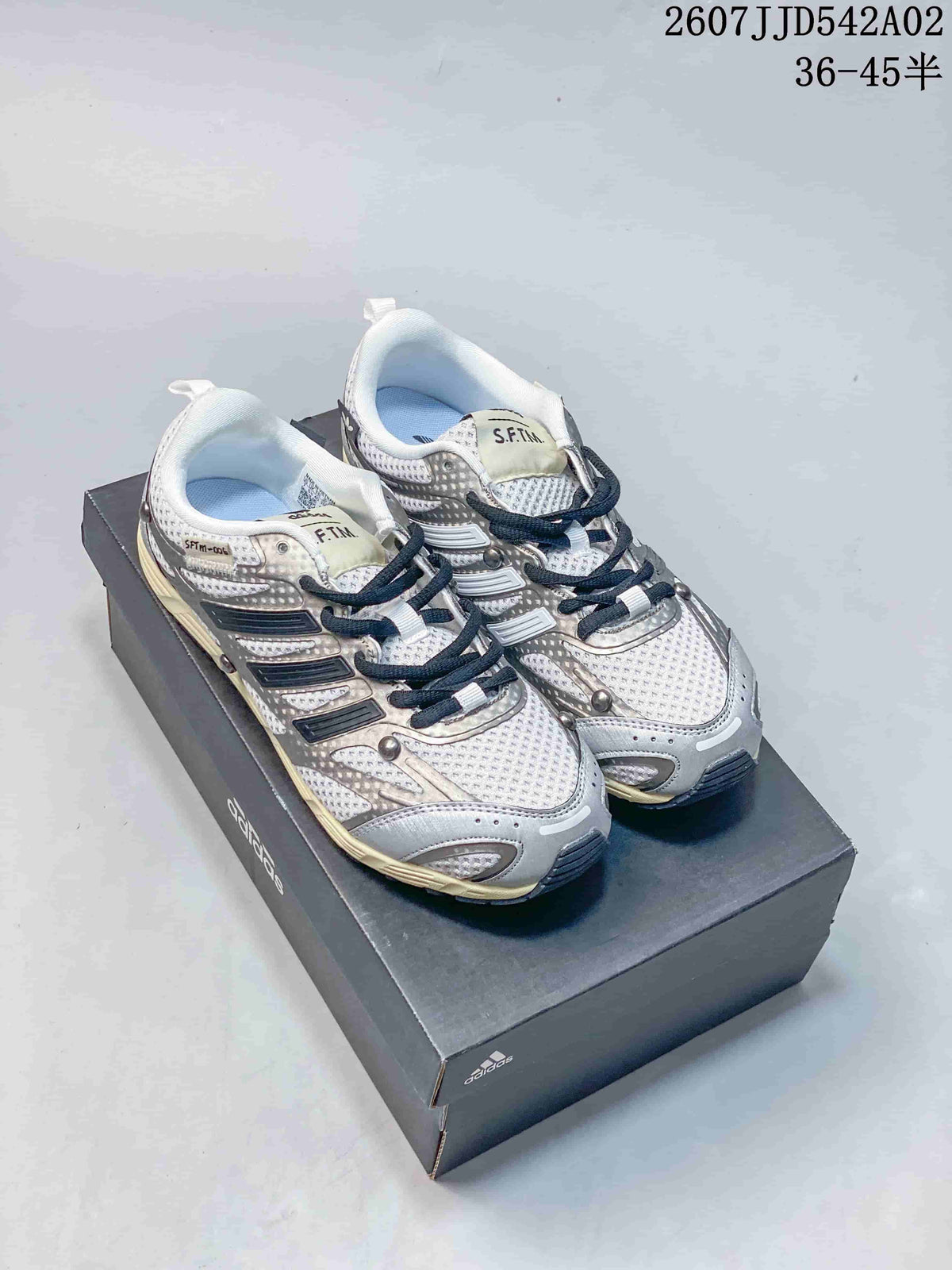 Pair of silver-toned adidas Adizero PR SFTM sneakers on a shoebox