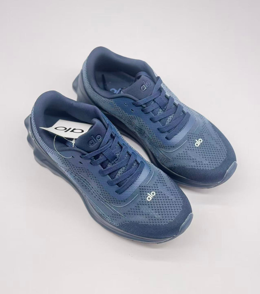 Top-down view of the dark blue Alo sneaker pair showing the laces, padded collars, and patterned uppers.