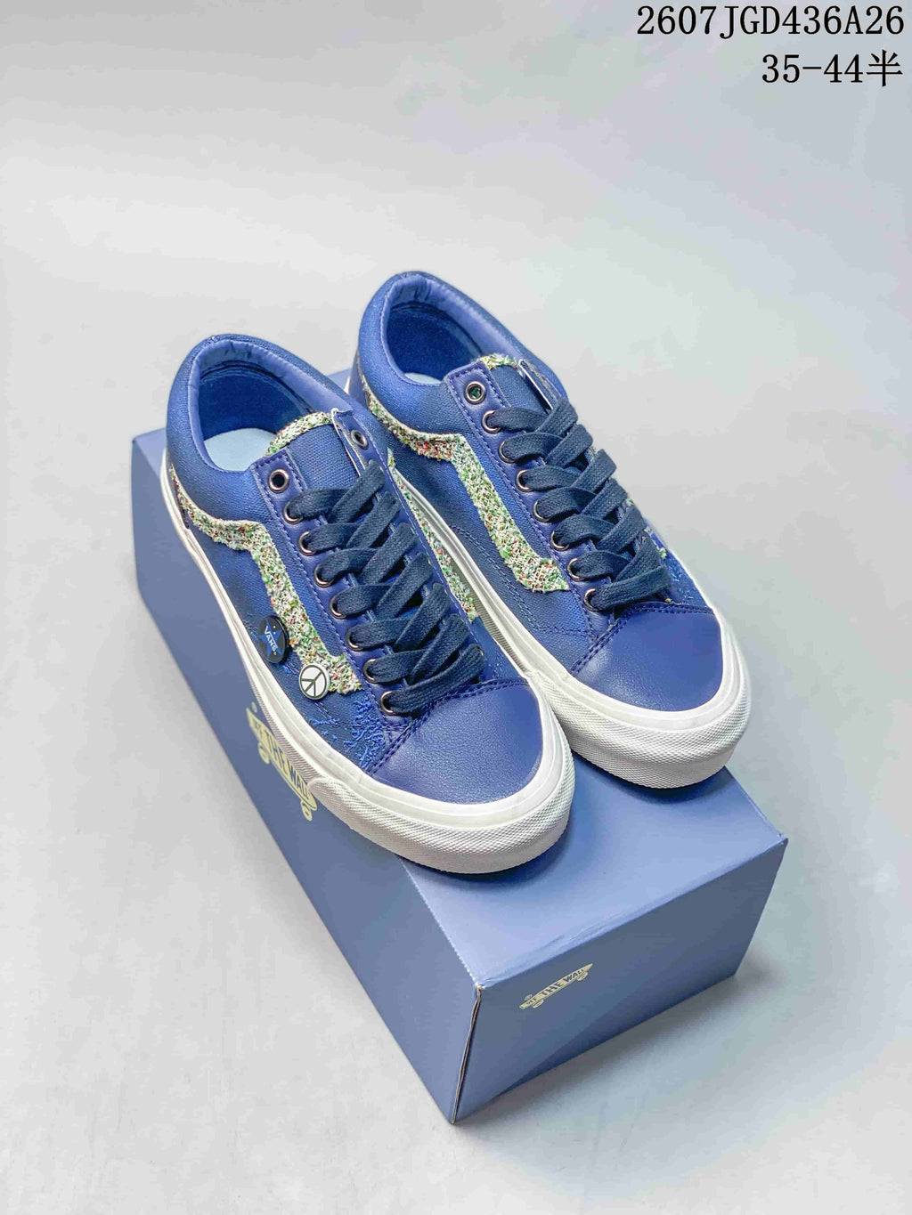 Pair of blue Vans Old Skool sneakers with multicolor side stripes displayed on a shoe box; image text shows style code 2607JGD436A26 and size range 35–44.5.