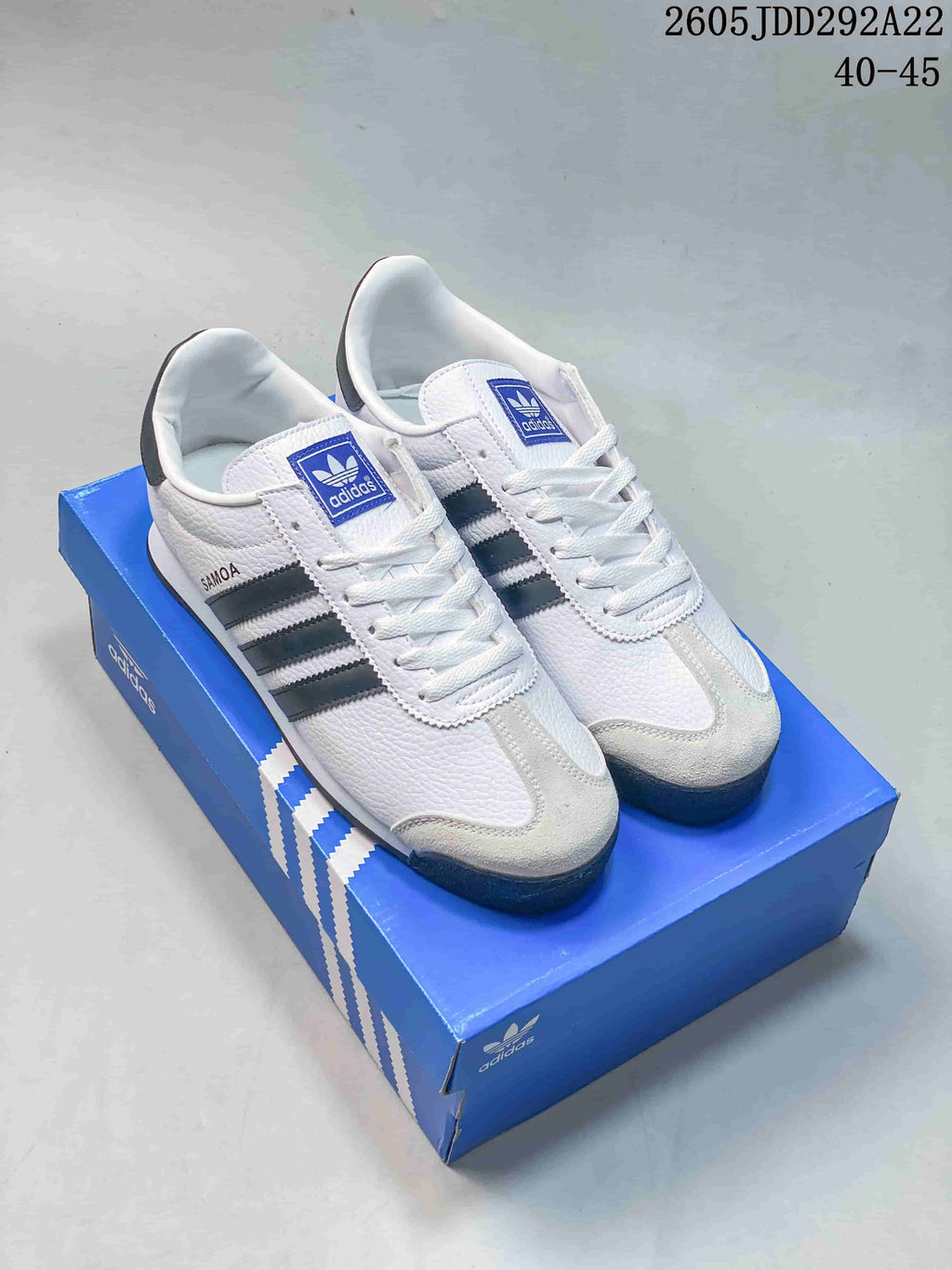 Pair of white and black adidas Originals Samoa sneakers displayed on a blue shoe box; overlay shows 40–45 and code 2605 JDD292A22.
