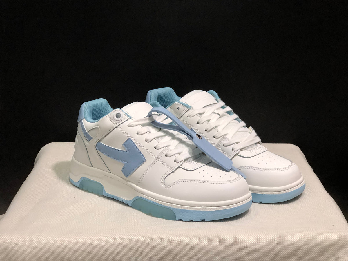 Three-quarter front view of the white and light blue sneaker pair with a light blue zip-tie-style accessory.