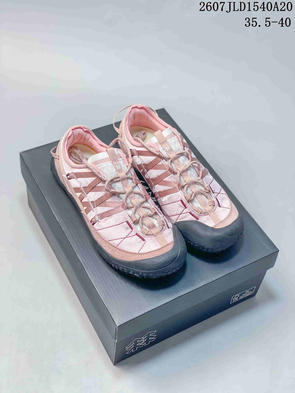 Pair of pink KOLON SPORT sneakers displayed on a black shoebox, showing the layered upper and black protective outsole.