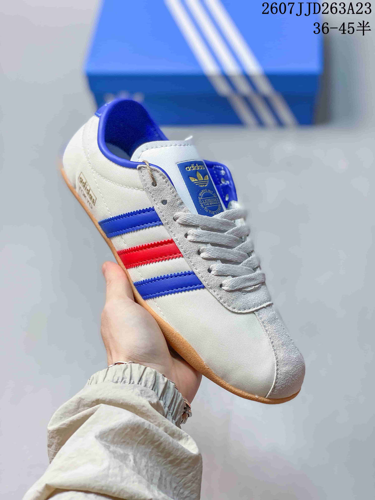 Angled side view showing the white upper, blue and red stripes, lacing, and gum-colored outsole.