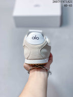 Rear view of the beige sneaker showing the white heel panel, Alo branding and gum outsole edge.