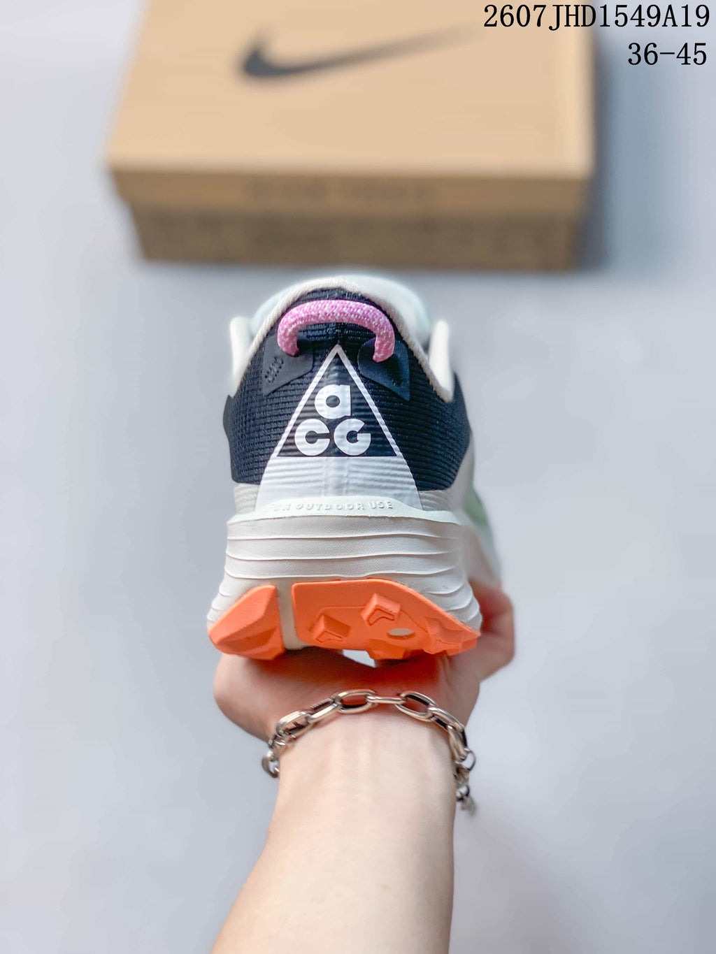Rear view showing the padded white collar, dark heel panel, triangular branding detail and orange outsole.