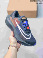 Angled side view showing the dark charcoal upper, white swoosh, tan and red side accents and blue outsole details.