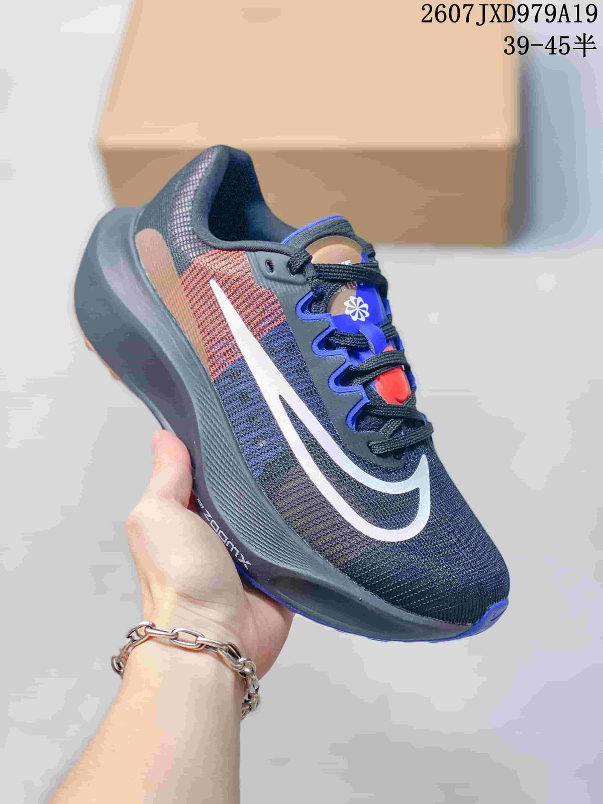 Angled side view showing the dark charcoal upper, white swoosh, tan and red side accents and blue outsole details.