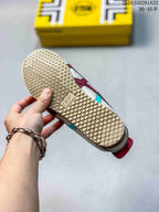 Underside of an Onitsuka Tiger sneaker showing the textured gum-colored outsole and yellow shoe box in the background.