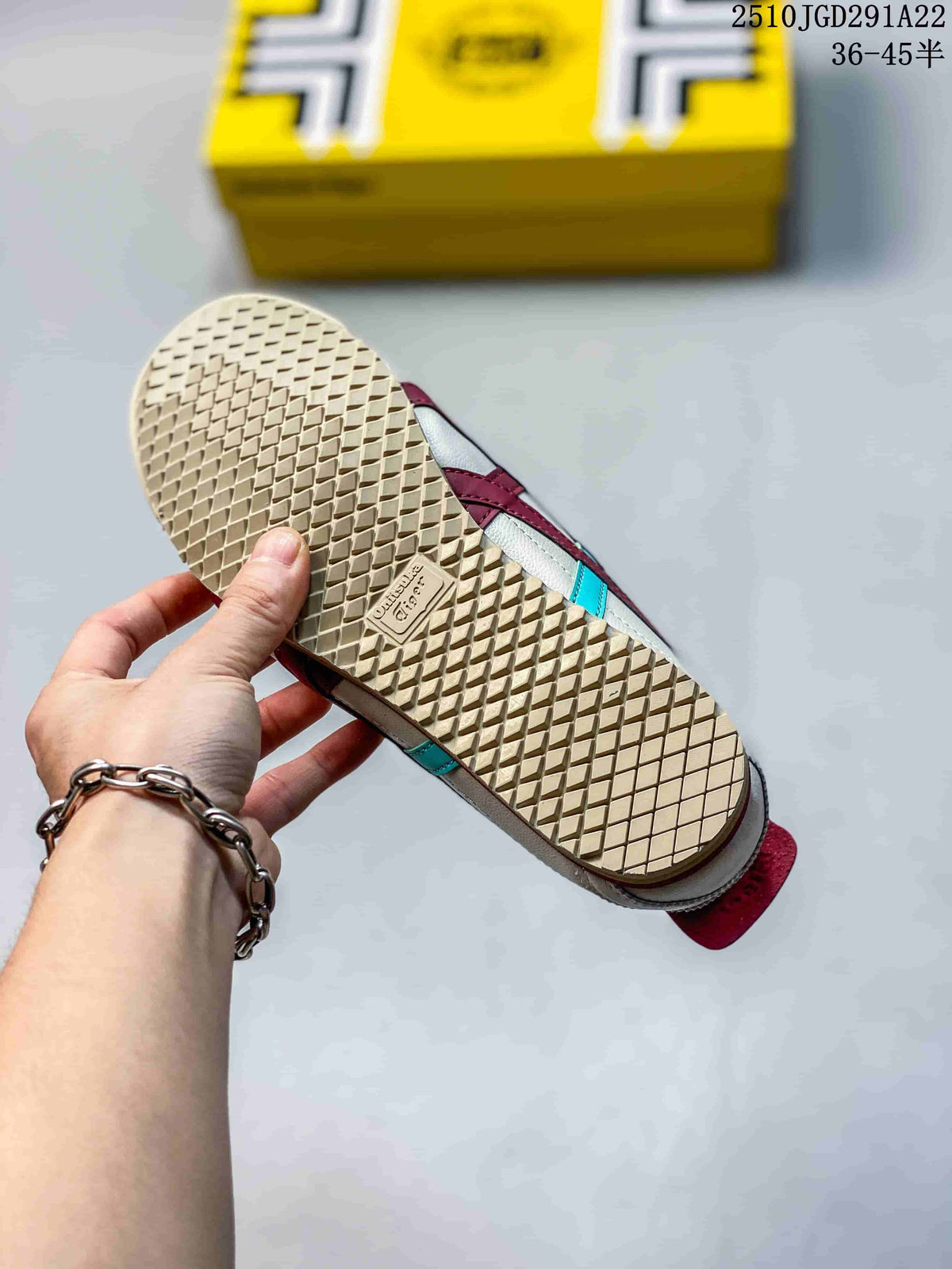 Underside of an Onitsuka Tiger sneaker showing the textured gum-colored outsole and yellow shoe box in the background.