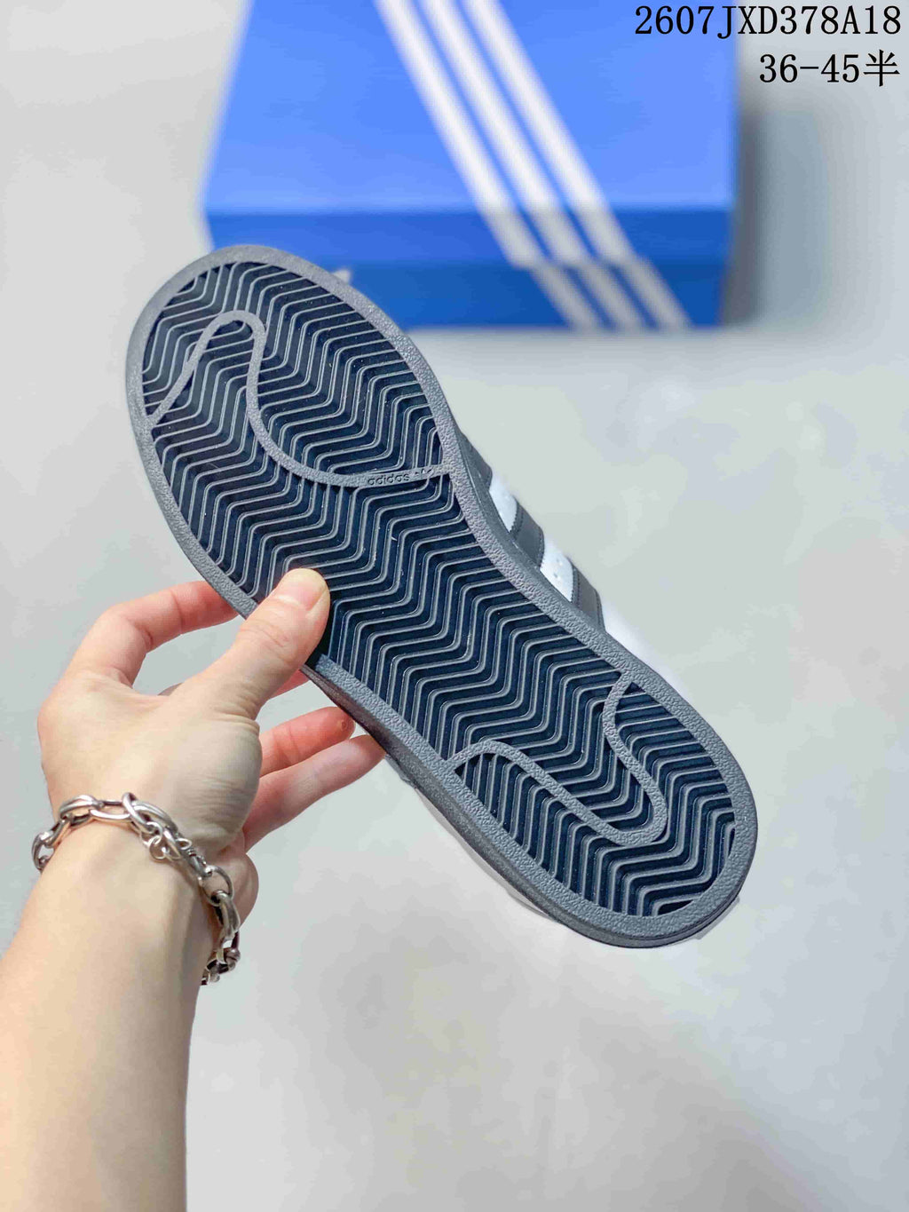 Close-up of the patterned black rubber outsole on a white and black Superstar sneaker.