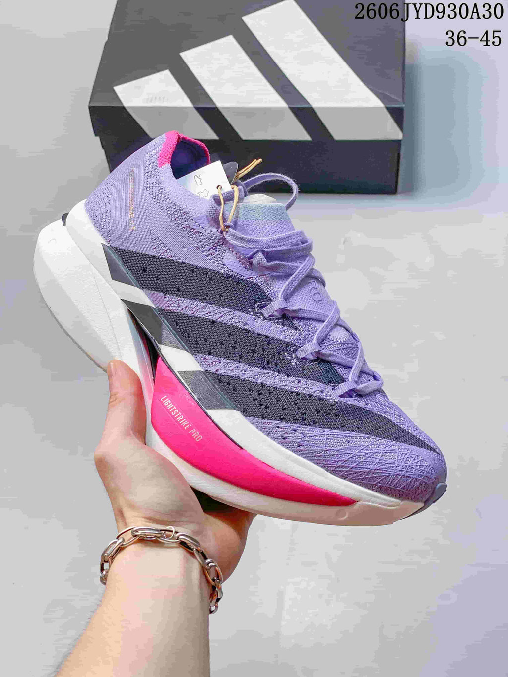 Lavender adidas Adizero Prime X3 shoe with dark stripes and a bright pink sole accent.