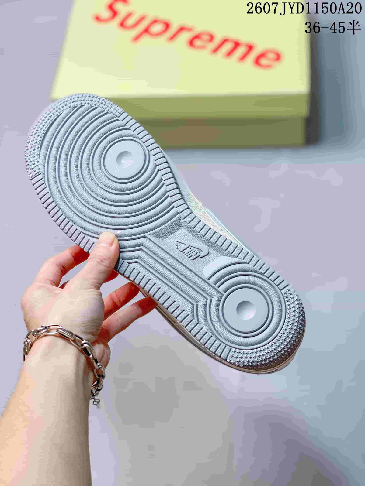 Close view of the grey rubber outsole with concentric traction circles and a pale yellow box marked Supreme in the background.