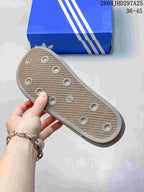 Underside of the mule slide showing a textured traction outsole and the blue adidas shoebox.