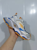 New Balance 9174 sneaker shown at an angle, highlighting the layered white and grey upper with orange and blue accents.