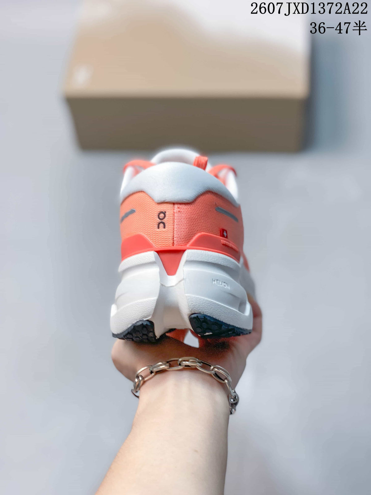 Rear view of a coral and white On running sneaker showing the padded heel and layered sole.