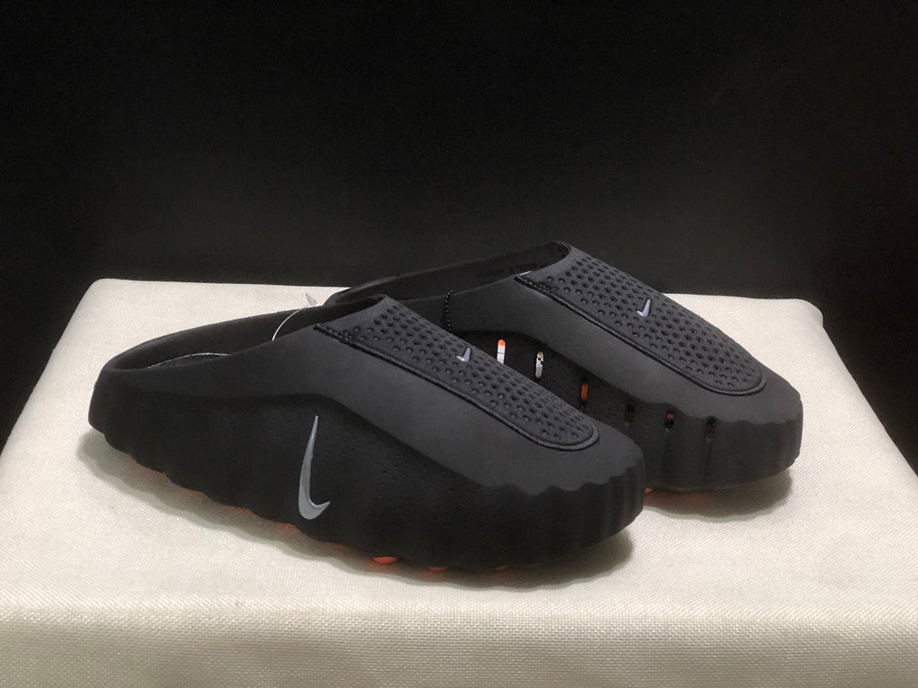 Three-quarter product view of the black closed-toe slides with textured straps and side Nike branding.
