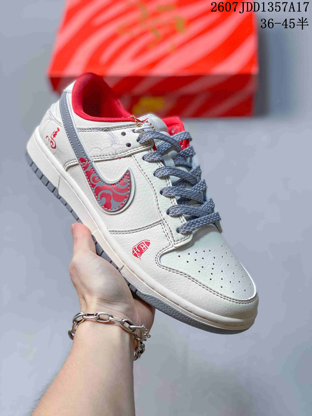 Cream and white low-top sneaker with red patterned side detailing, grey laces and a red padded collar.