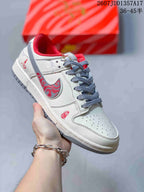 Cream and white low-top sneaker with red patterned side detailing, grey laces and a red padded collar.
