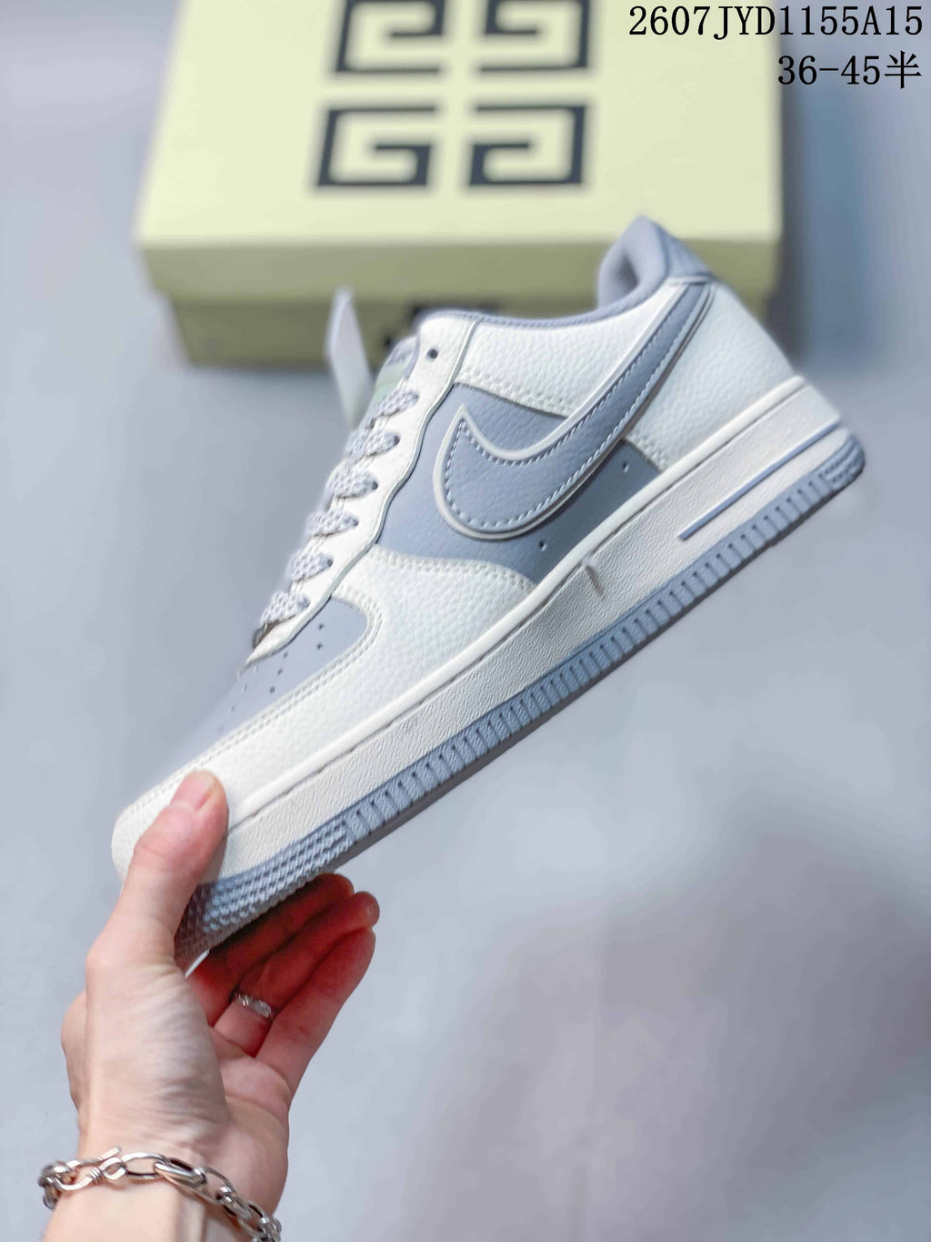 Side view of the sneaker showing the layered gray and blue-gray upper, patterned Swoosh panel, white midsole, and gray outsole.