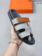 Close view of a Hermès Kazimir slide sandal with a tan accent strap.