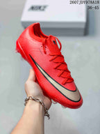 Angled front view of a red Nike Mercurial soccer cleat with red laces and black-and-gold swoosh detailing.