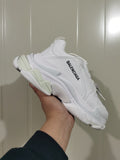 Angled view of a white Balenciaga sneaker showing the side branding, layered panels, and textured sole.
