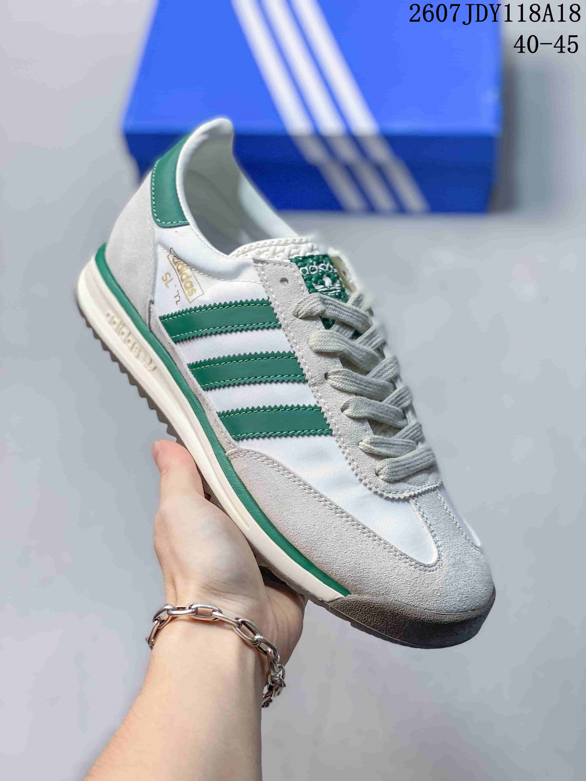Angled side view of the white and green adidas sneaker showing the three stripes, textured overlays, green trim, and dark outsole edge.
