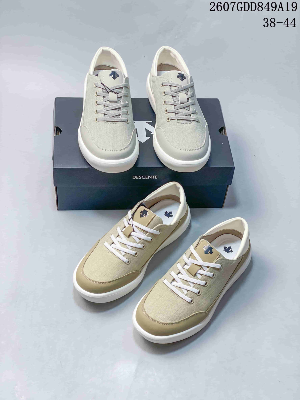 White and beige Descente sneakers arranged together, showing the front profiles, lace systems, logos, shoebox, and style code 2607GDD849A19.
