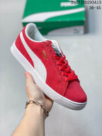 Angled side view of the red sneaker showing the white formstrip, gold side branding, laces, and white outsole.