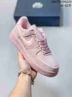 Angled side view of the soft pink Nike low-top sneaker showing the Swoosh, laces, and padded collar.
