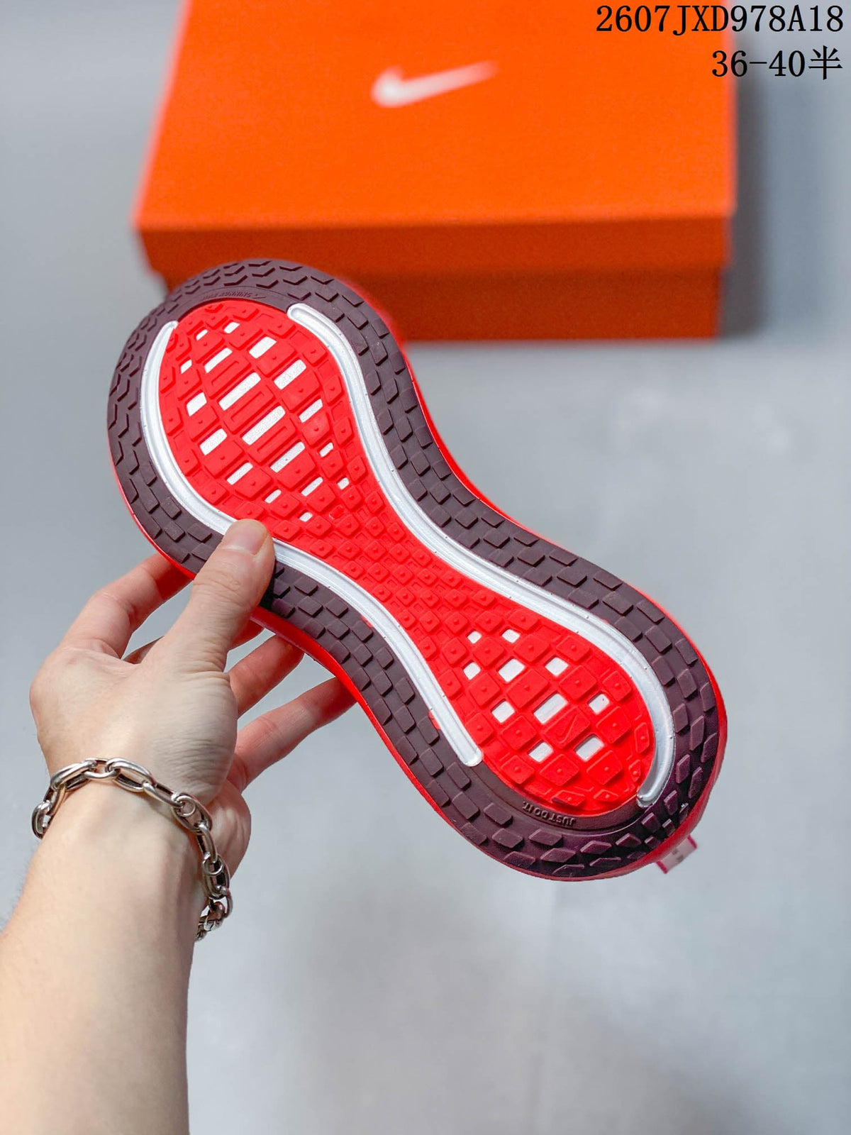 Underside of the sneaker showing a red and dark tread outsole with contrasting white traction sections.