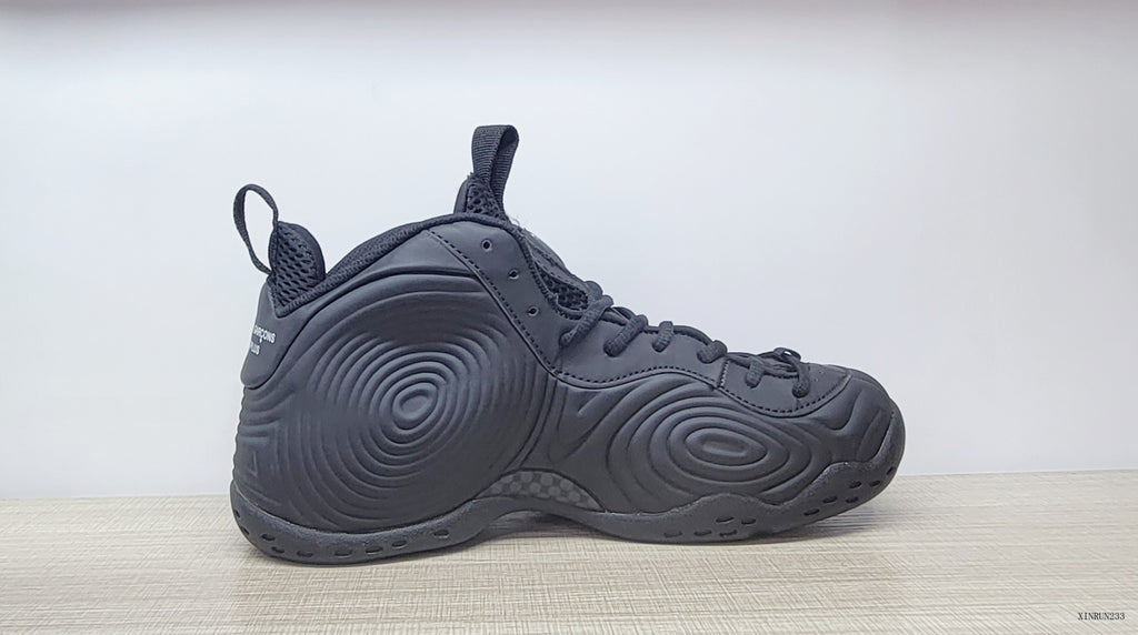 Side profile of a black high-top sneaker with raised circular panel details.