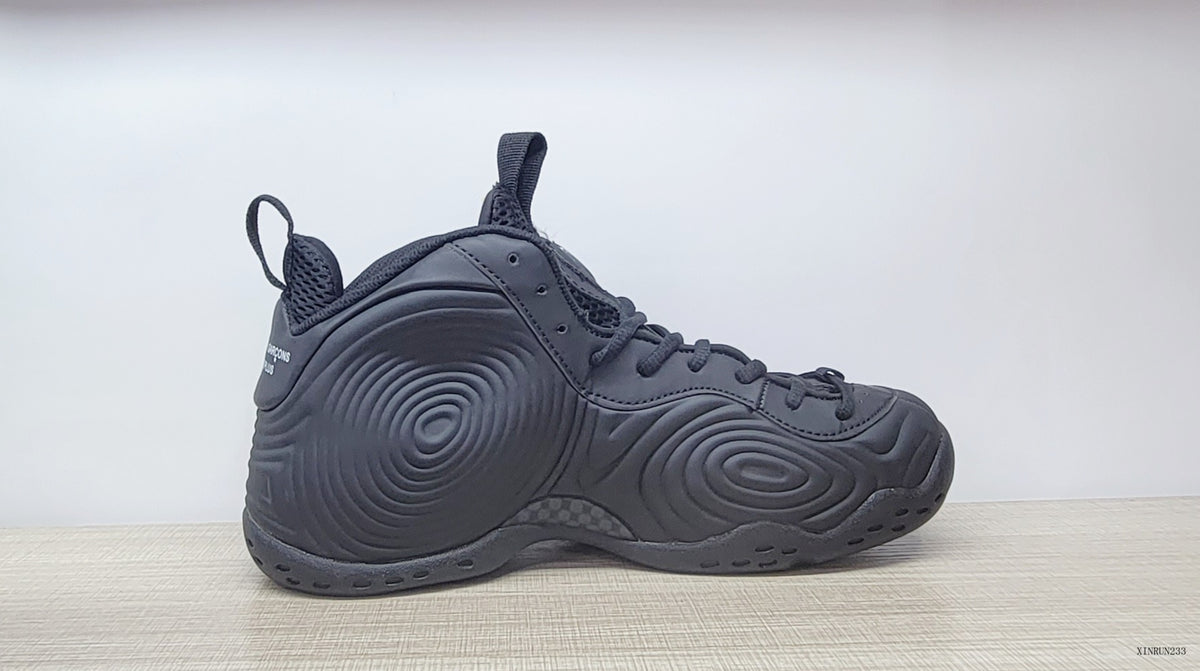 Side profile of a black high-top sneaker with raised circular panel details.