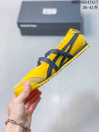 Side profile showing the low silhouette, black double straps, buckle closures and yellow outsole.