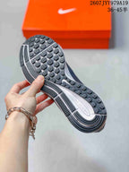 Outsole view showing the black patterned traction surface and segmented white-and-gray midsole.
