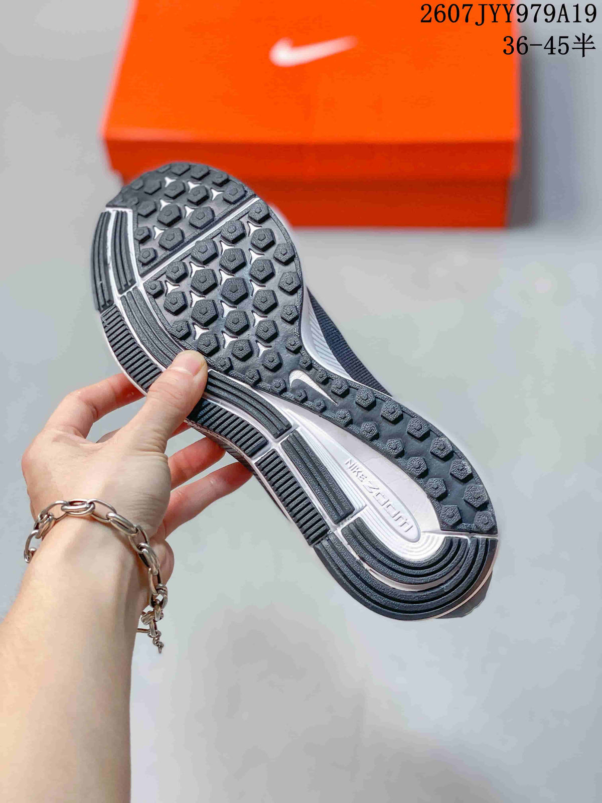 Outsole view showing the black patterned traction surface and segmented white-and-gray midsole.