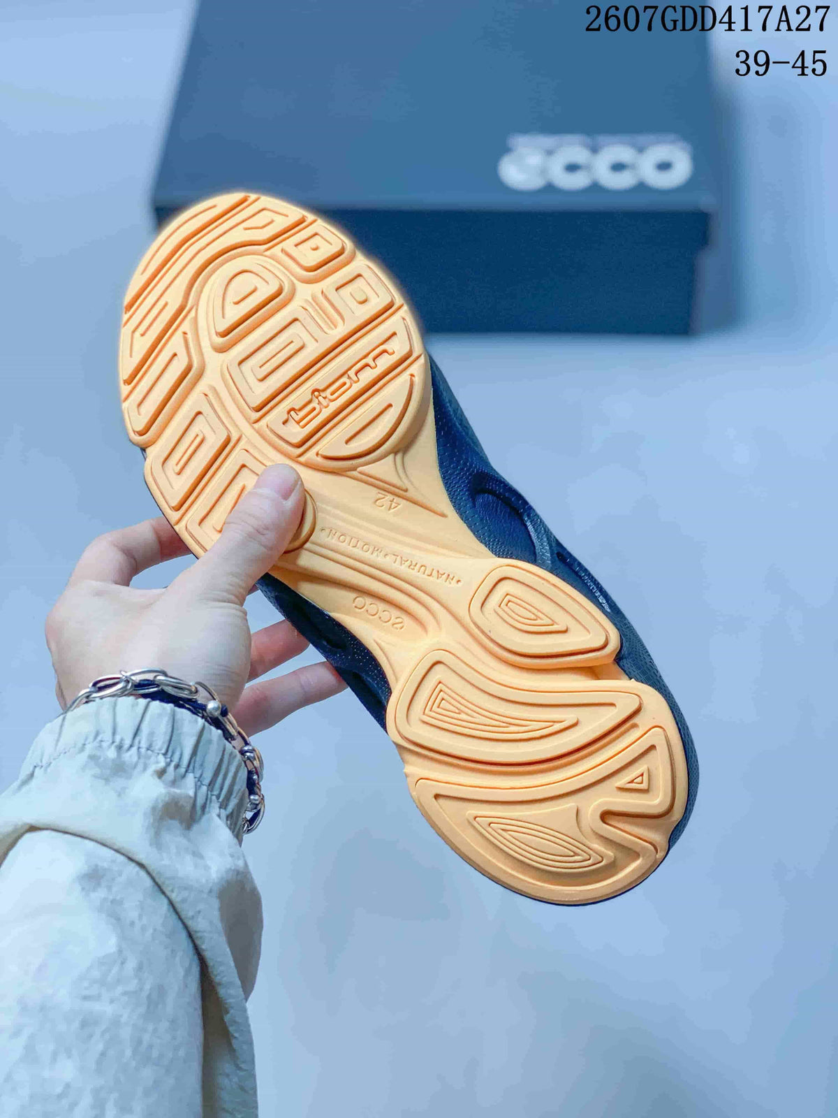 Bottom view of a black ECCO BIOM sneaker showing the tan patterned outsole and traction grooves.