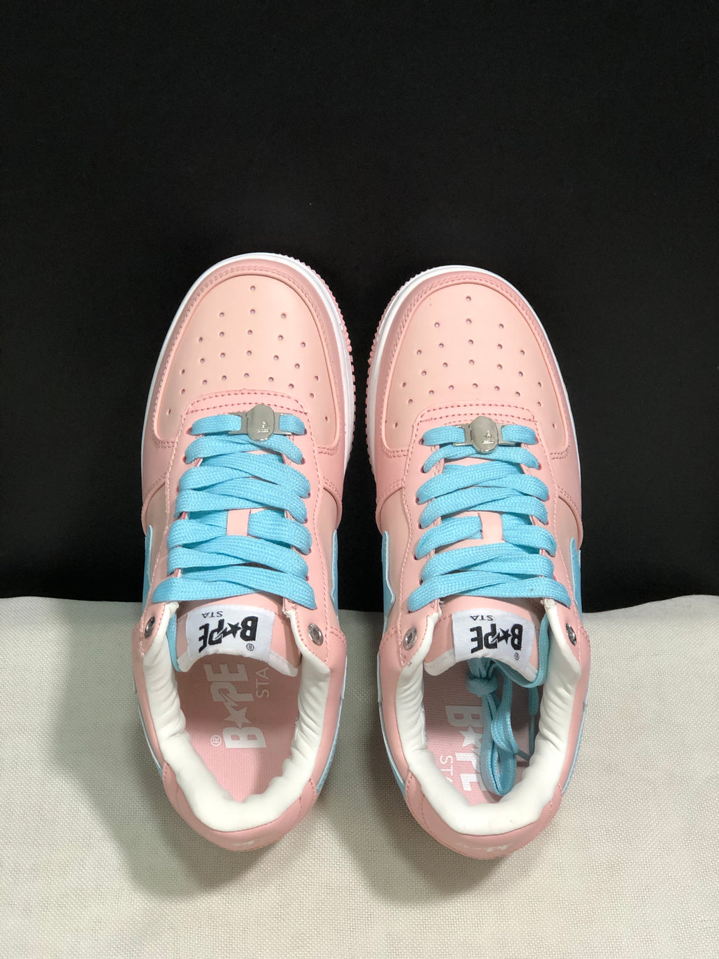 Top-down view showing the perforated pink toe boxes, light-blue laces, metal lace details, and branded tongues.