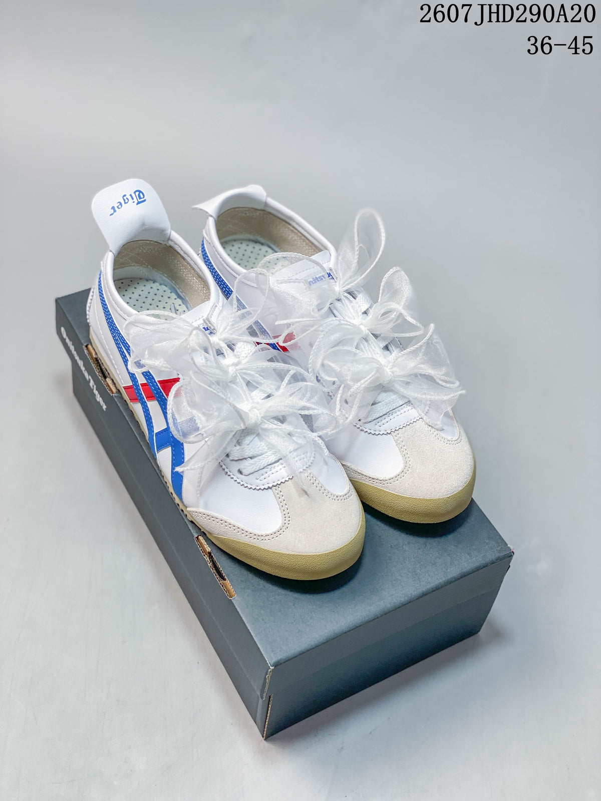 Pair of white Onitsuka Tiger sneakers with blue and red stripes, ribbon-style laces, and a shoebox.
