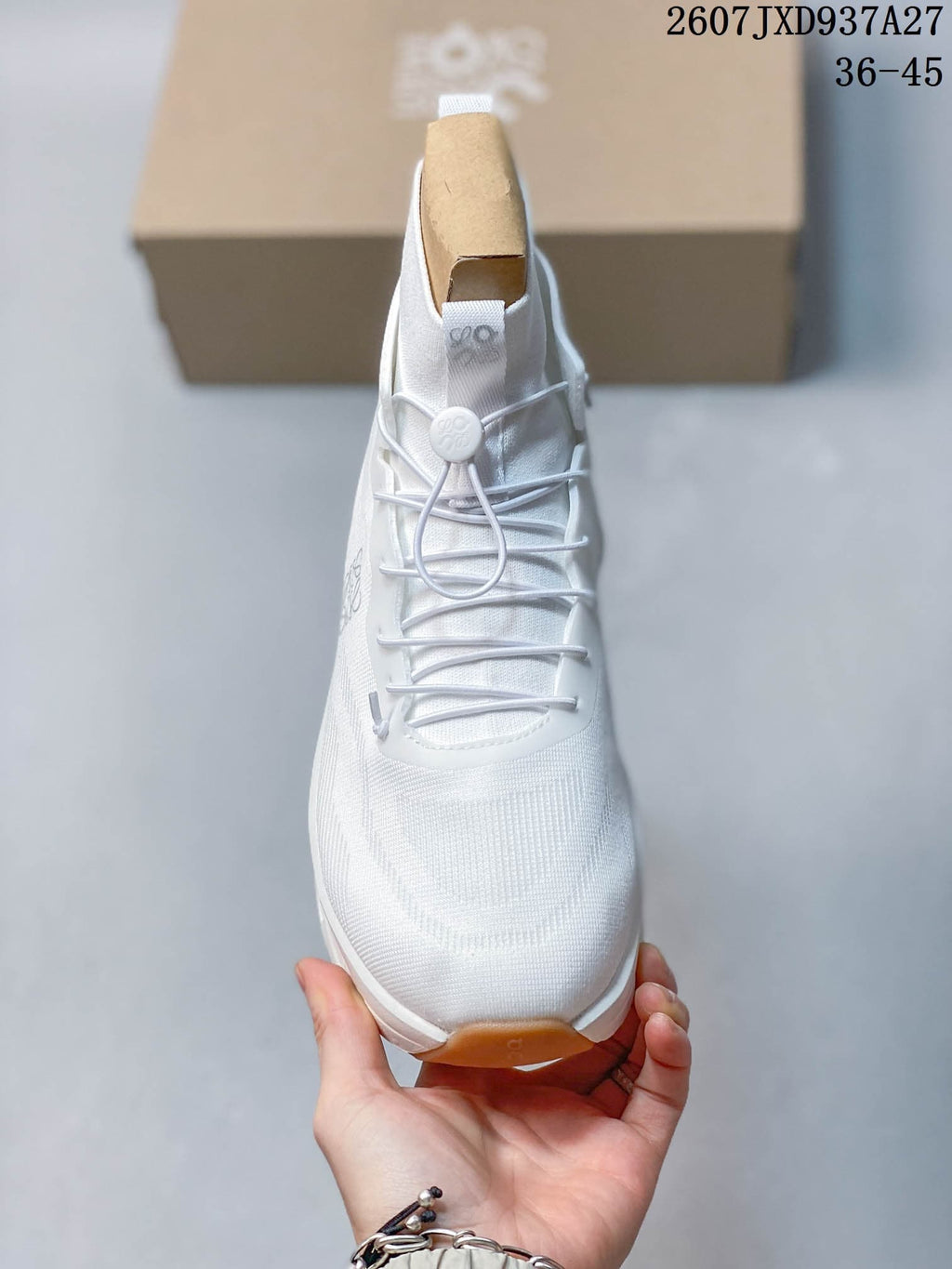 Front view of the white sneaker showing the rounded toe, lace-up front, toggle closure, and gum-colored outsole section.