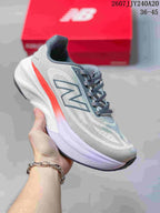 Gray and white New Balance running sneaker with a bright coral side accent and dark gray branding, shown with a red shoe box.