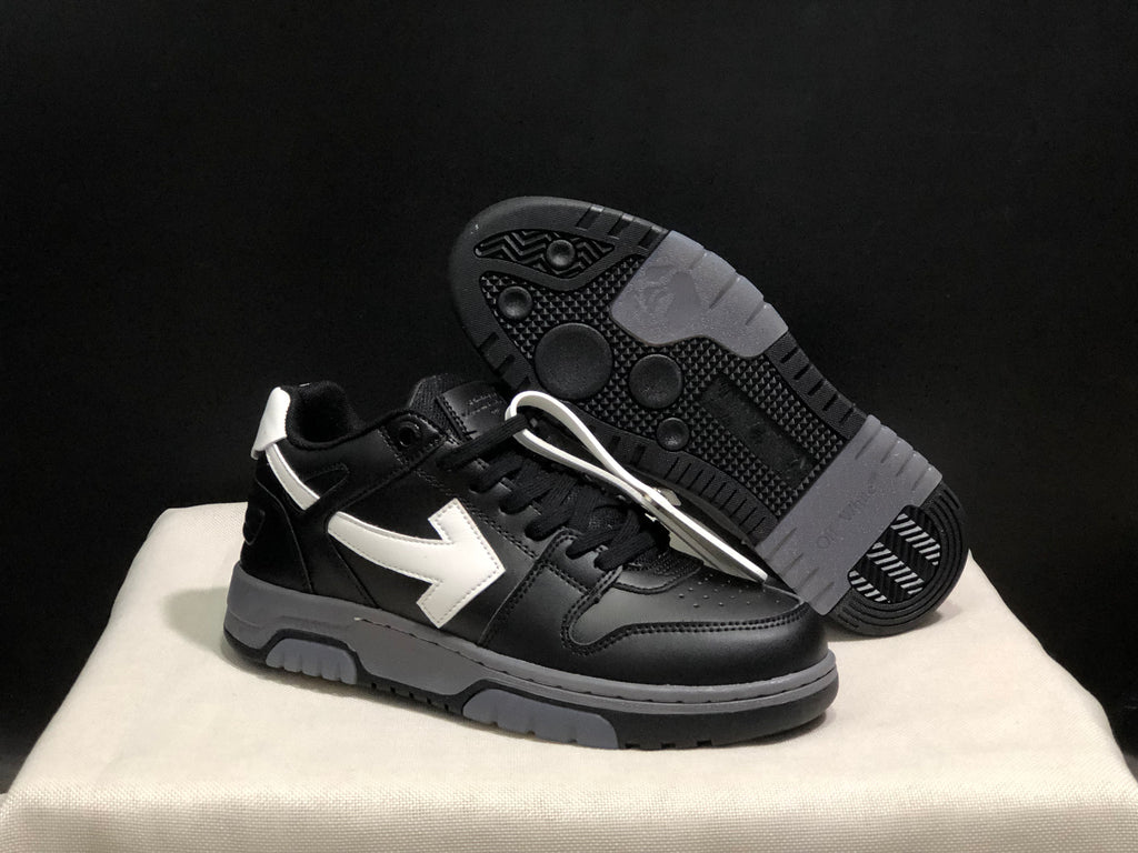 Angled view of one black sneaker with its textured black-and-gray outsole visible behind it.